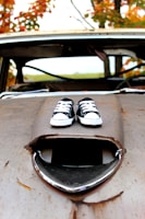 Close-up of a colorful clown shoe resting on a classic car hood.