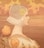 A profile of a woman wearing an ornate lace bonnet, with delicate floral patterns and geometric designs. Her gaze is serene, set against a softly colored background featuring windmills and a sky with fluffy clouds. In the foreground, there are large, stylized orange flowers with intricate leaves.