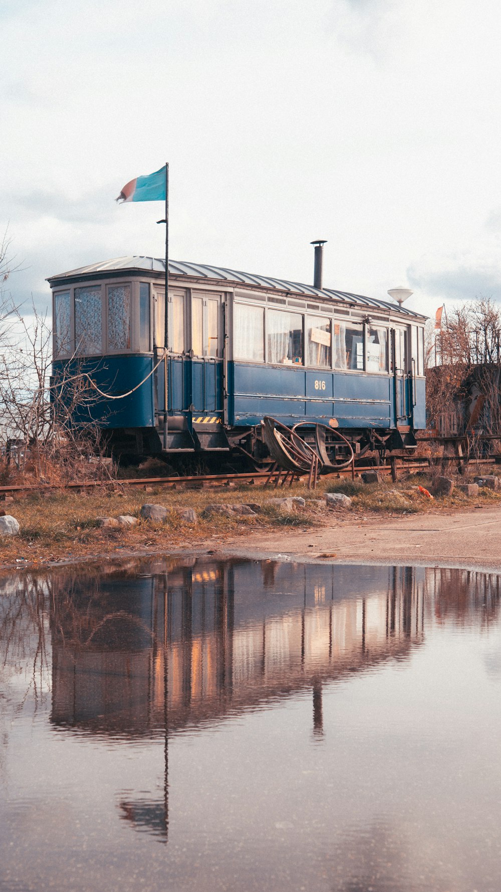 a blue train car sitting next to a body of water
