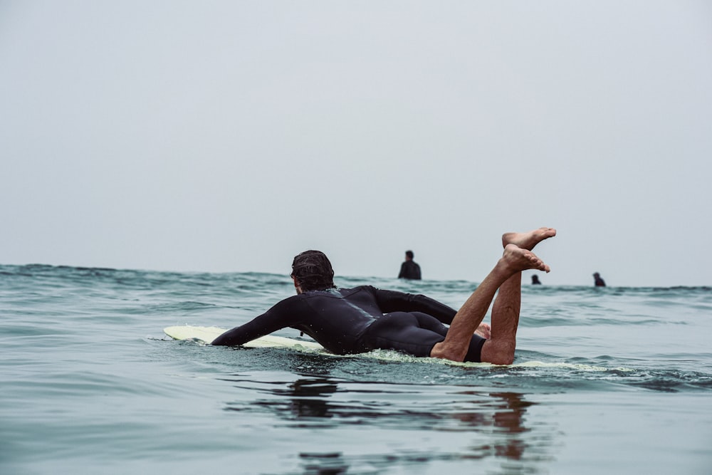 a man laying on a surfboard in the ocean