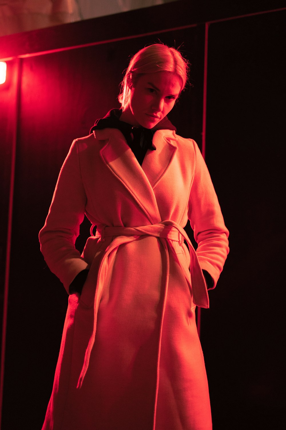 a woman in a long coat standing in a dark room
