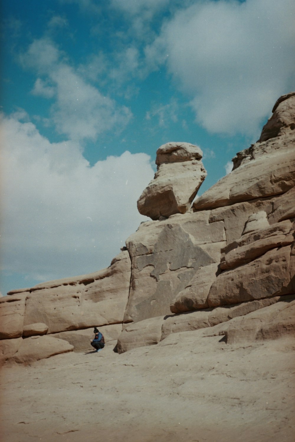 a person sitting on a rock formation in the desert