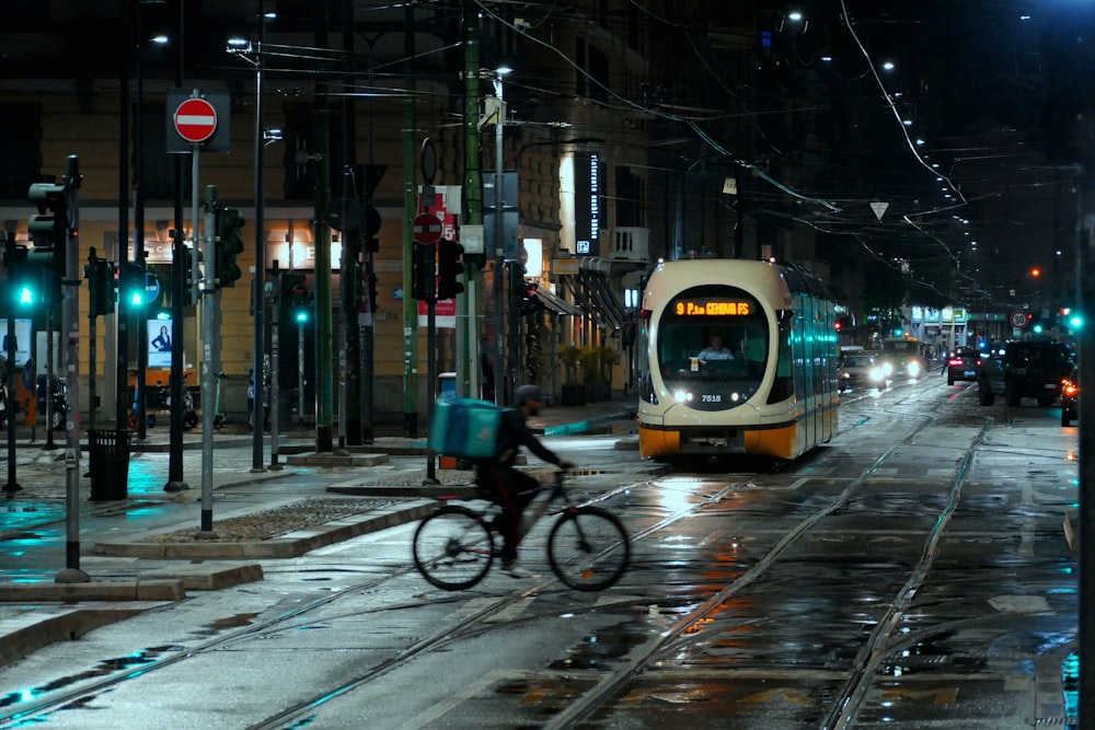 a man riding a bike down a street next to a train