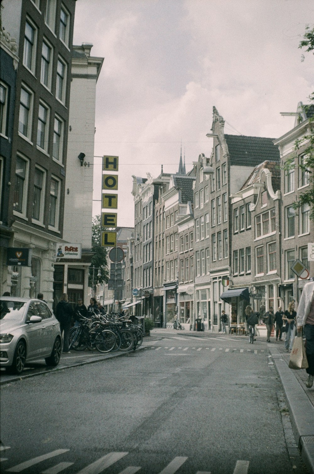 a group of people walking down a street next to tall buildings