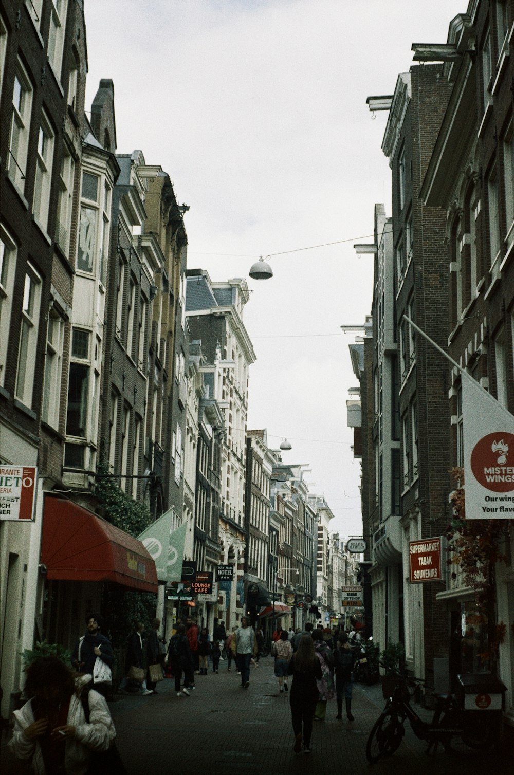 a group of people walking down a street next to tall buildings