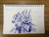 A detailed pen drawing on lined paper depicts a fox and a rabbit dressed in shirts and ties. The expressions are exaggerated and lively. The drawing is done entirely in blue ink and occupies the center of the page. In the corner, there's a handwritten date and some text.