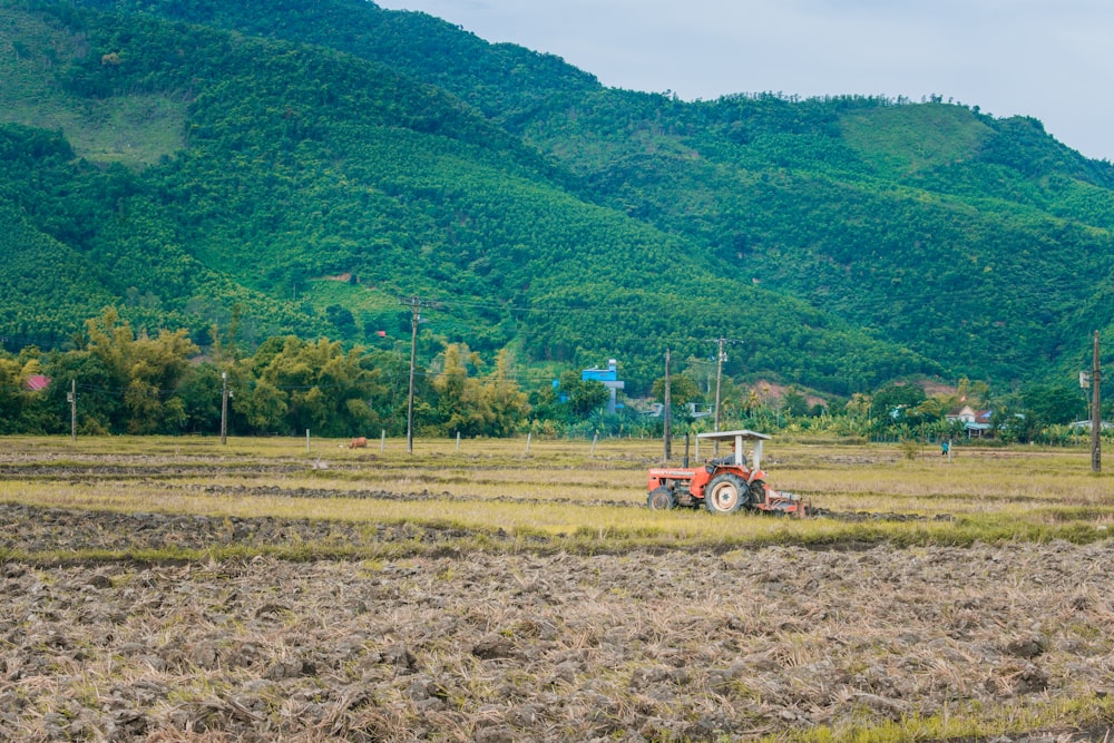 um trator em um campo com montanhas ao fundo