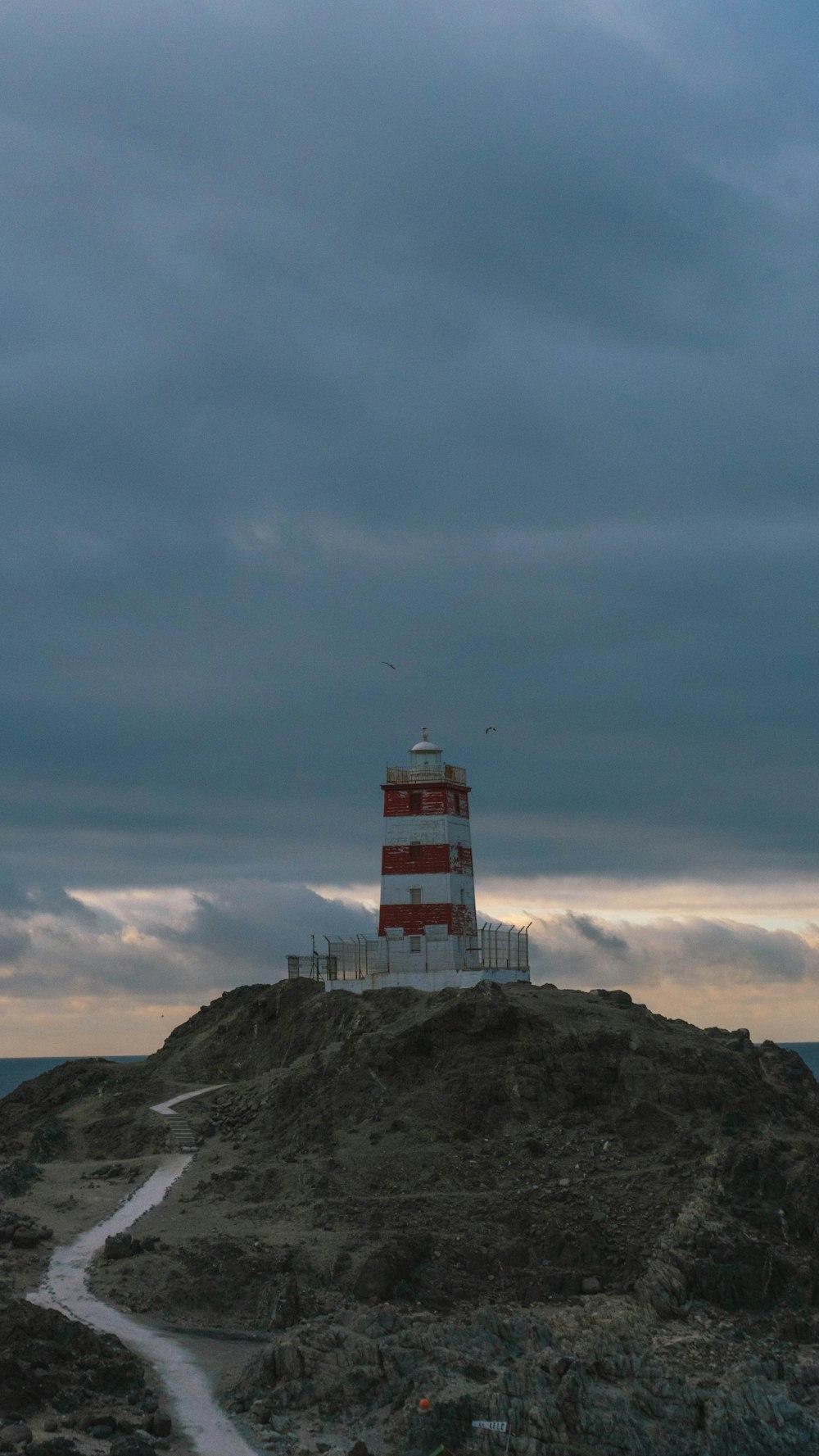 a red and white lighthouse on top of a hill