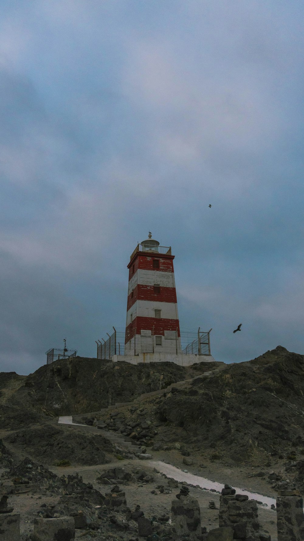 a red and white lighthouse on top of a hill