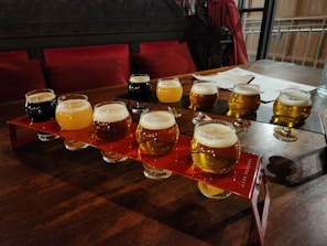 A variety of craft beer bottles and glasses arranged on a rustic wooden table.