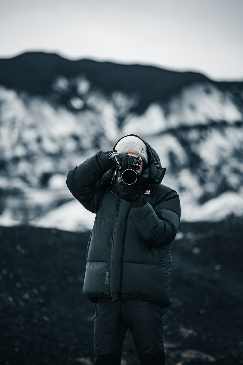 a person standing in front of a mountain taking a picture with a camera