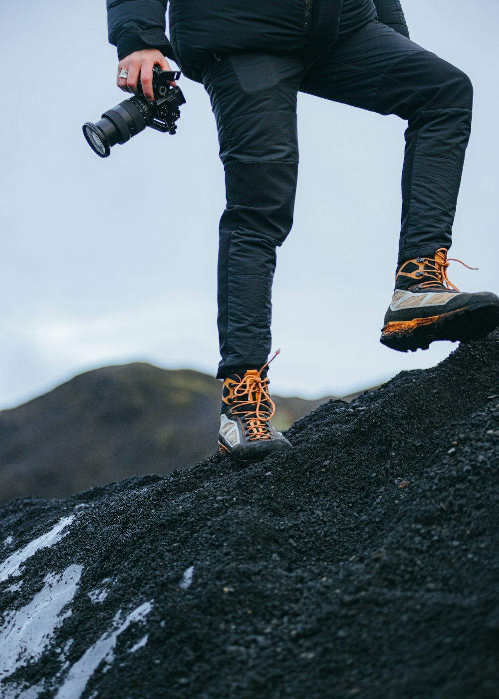 a man standing on top of a pile of black rocks