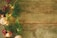 A rustic wooden surface adorned with festive decorations on the side, including pine branches, red berries, pinecones, and glowing lights, creating a seasonal and natural atmosphere.