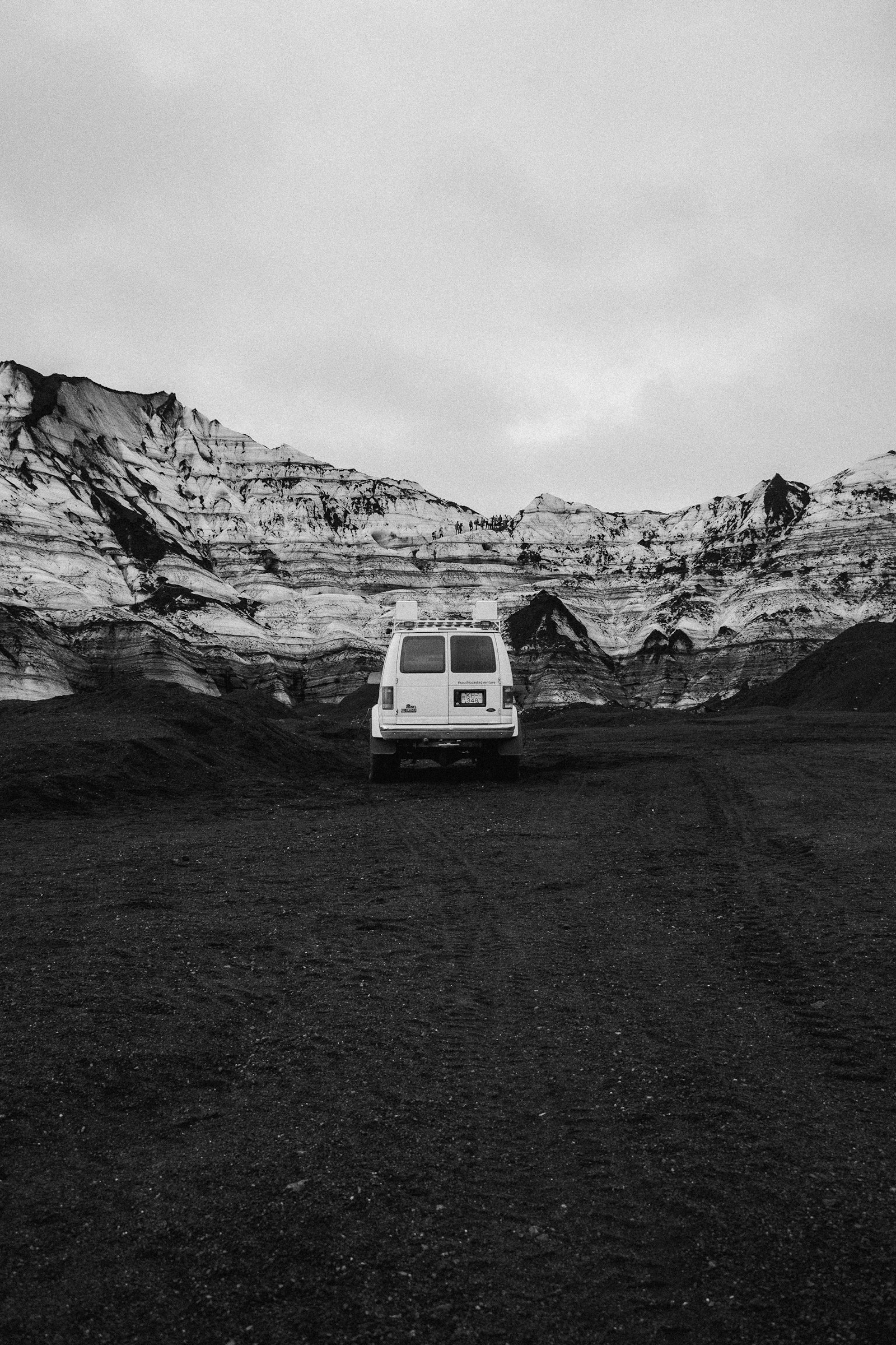 A lone camper van parked in a wide open grassy field in the Icelandic countryside