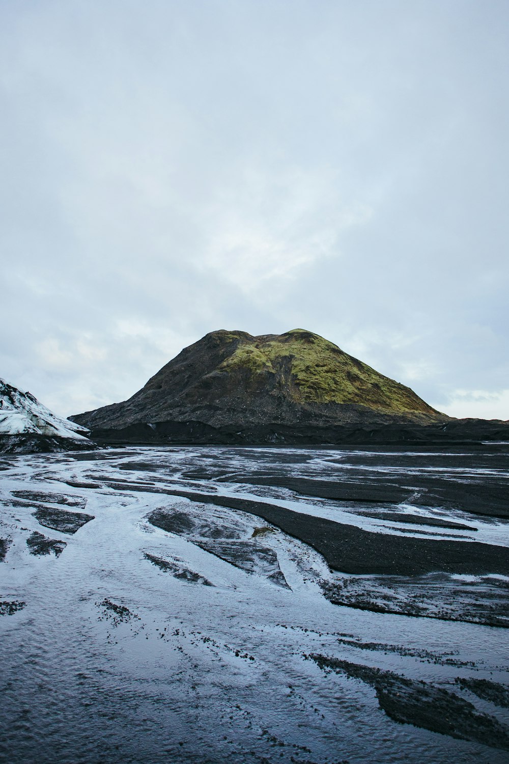 a mountain with snow on the ground and a hill in the background