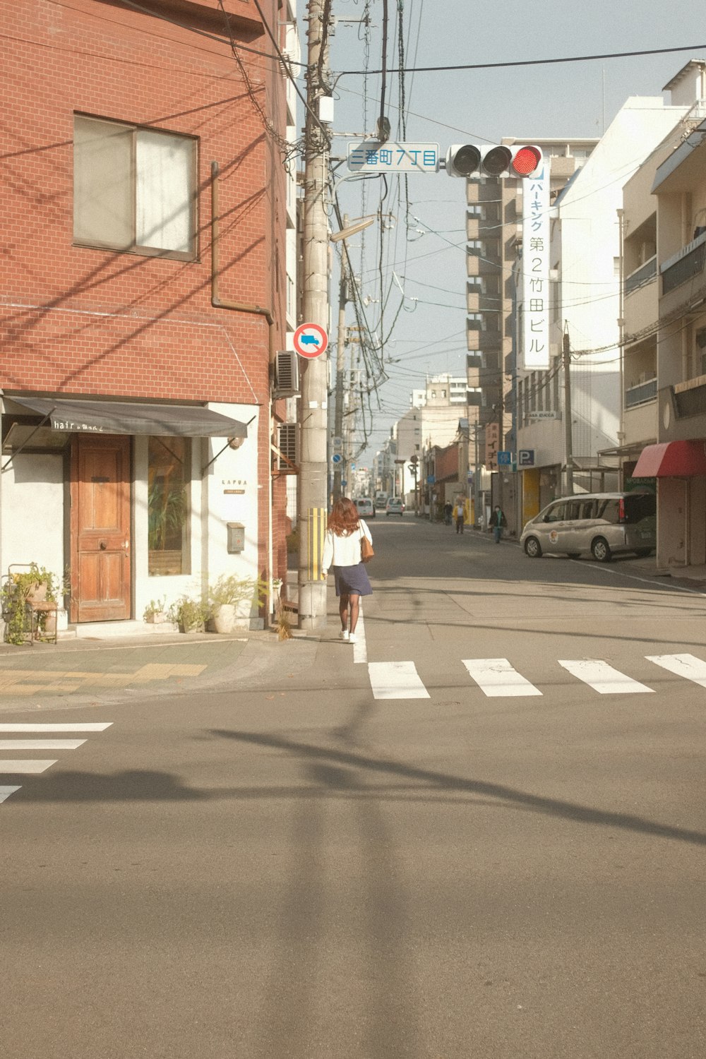 a woman walking down a street next to a traffic light