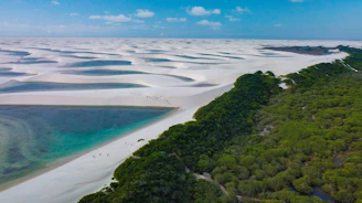 A vibrant sunset over the white dunes and turquoise lagoons of Lençóis Maranhenses, with a local guide leading a small group of travelers.