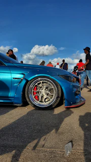 Happy customer standing next to their car, showing off freshly installed mags under a sunny sky.