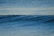 Close-up of a peaceful teacher smiling softly with ocean waves in the background.