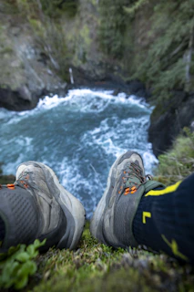 Trail trekking boots beside a bubbling mountain stream, ready for adventure.