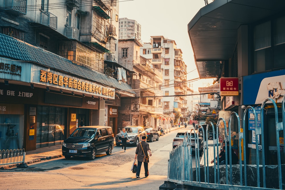 a couple of people walking down a street next to tall buildings