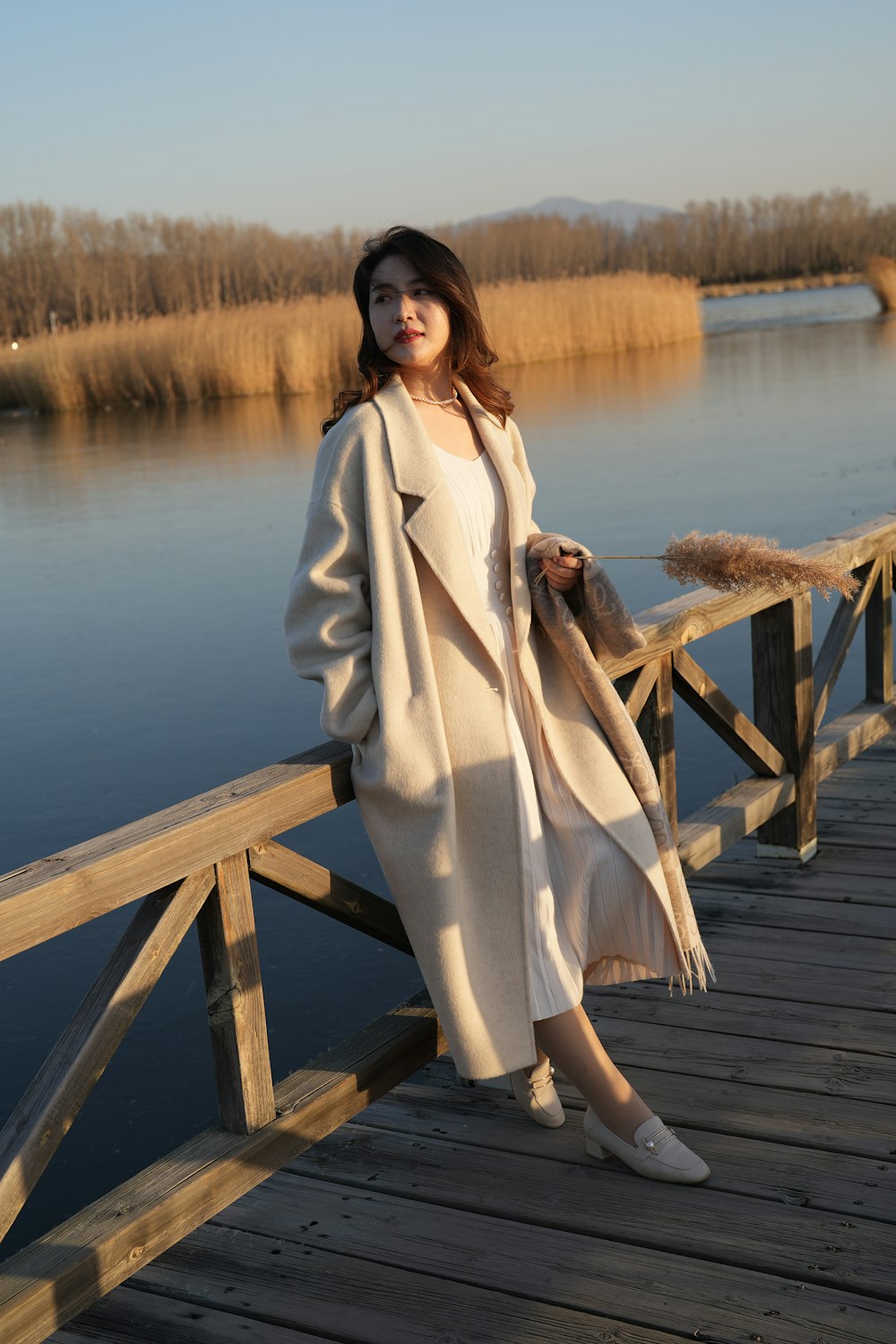 a woman standing on a wooden bridge next to a body of water
