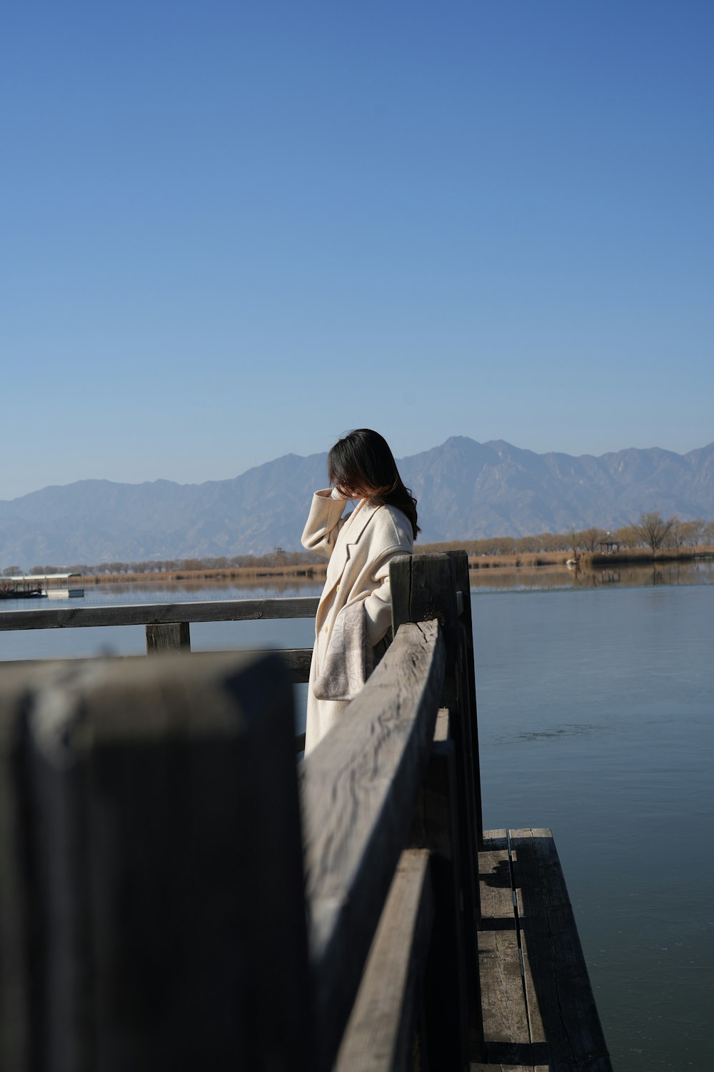 a woman sitting on a pier looking at the water