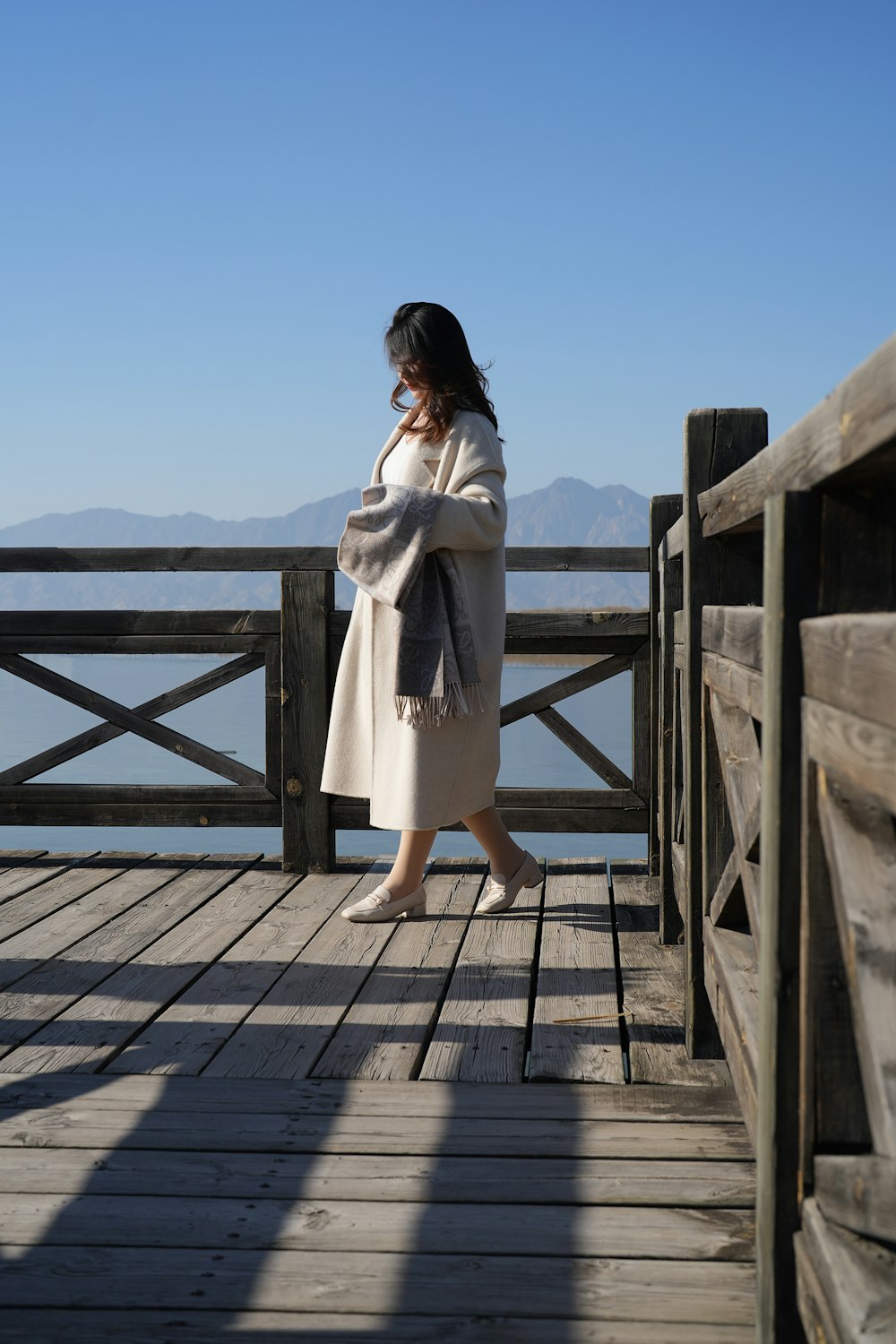 a woman standing on a wooden pier next to a body of water