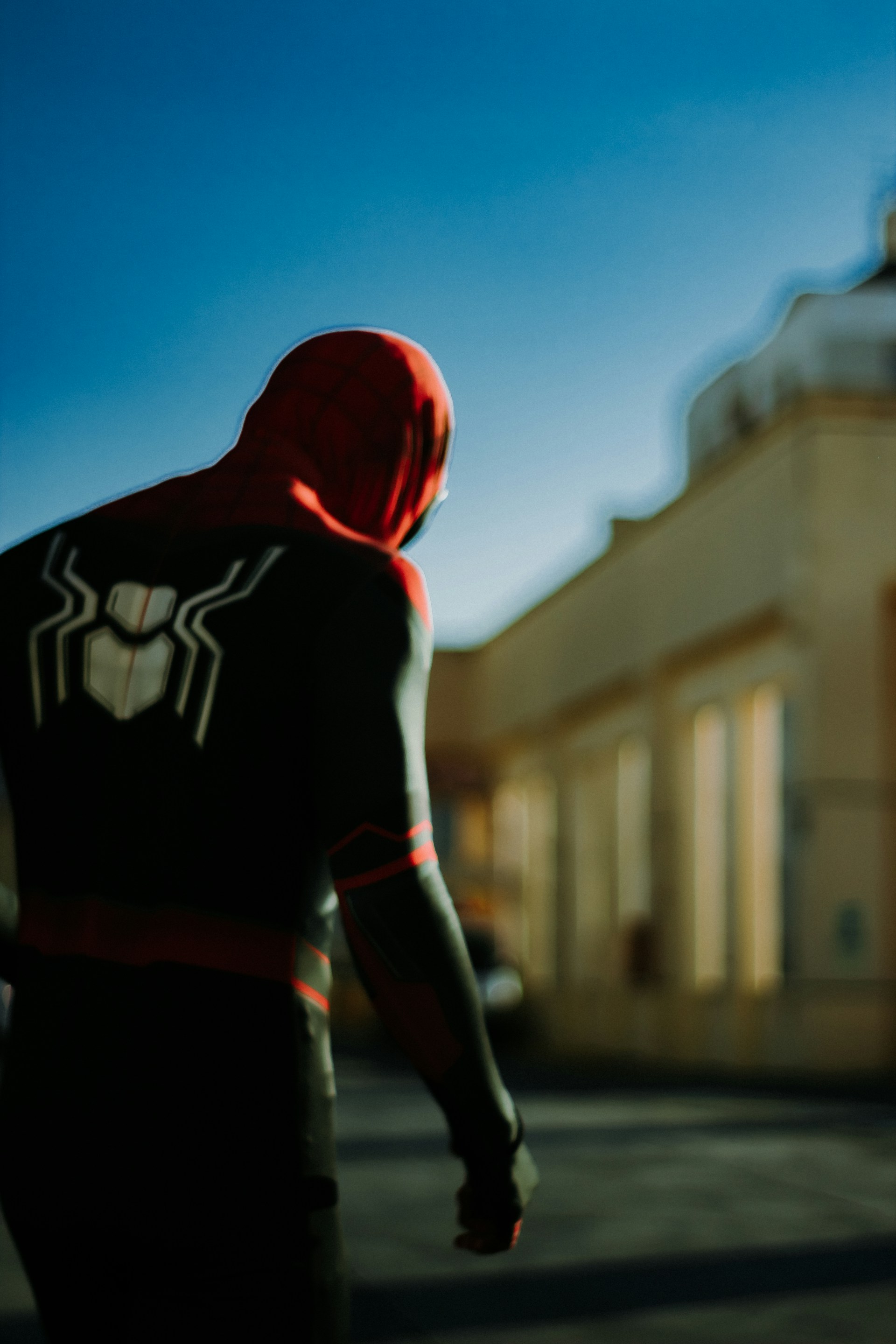 A dynamic shot of Spider-Man perched on a city rooftop at dusk, the red and blue suit vivid against the darkening sky.