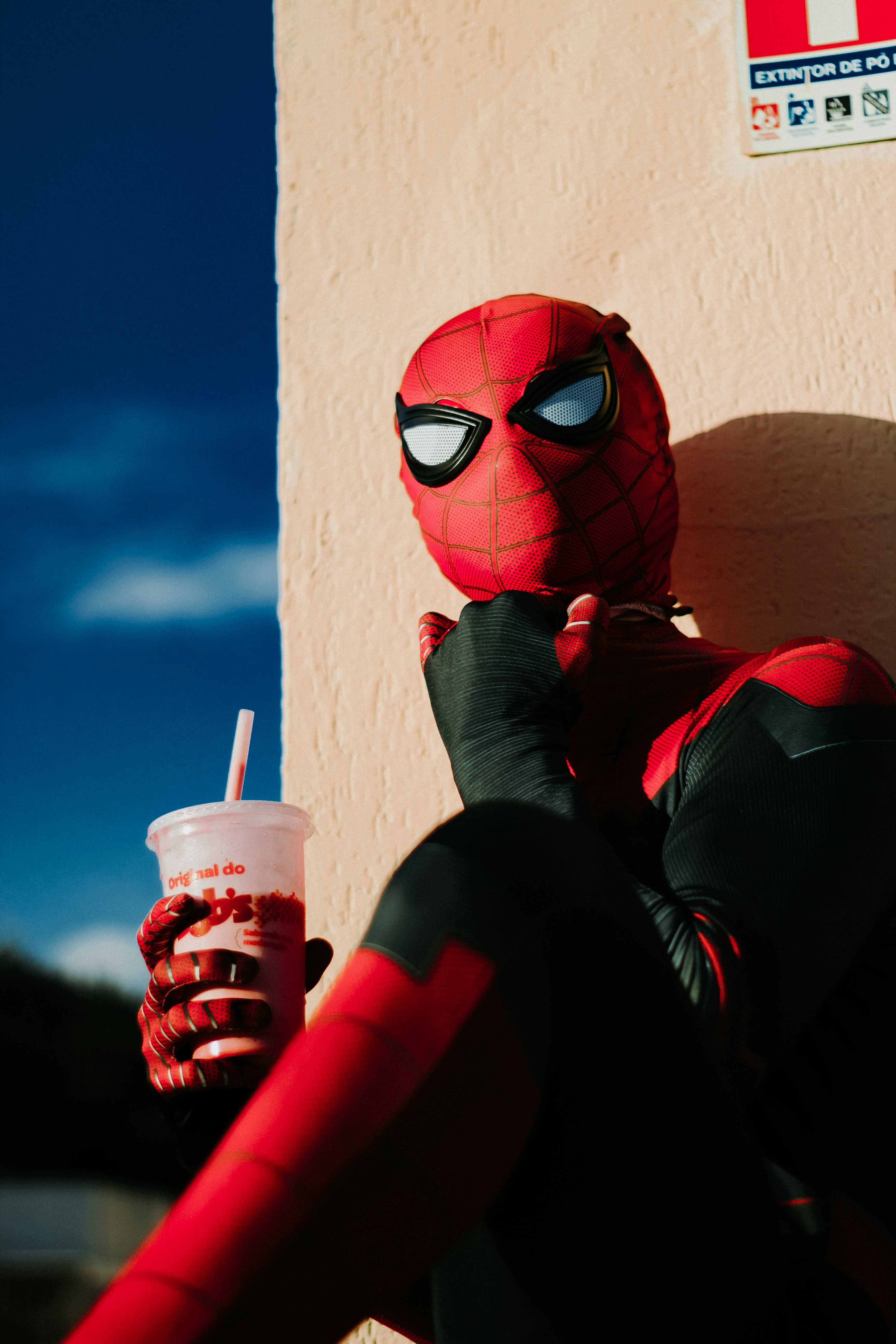 a person in a spiderman costume holding a drink