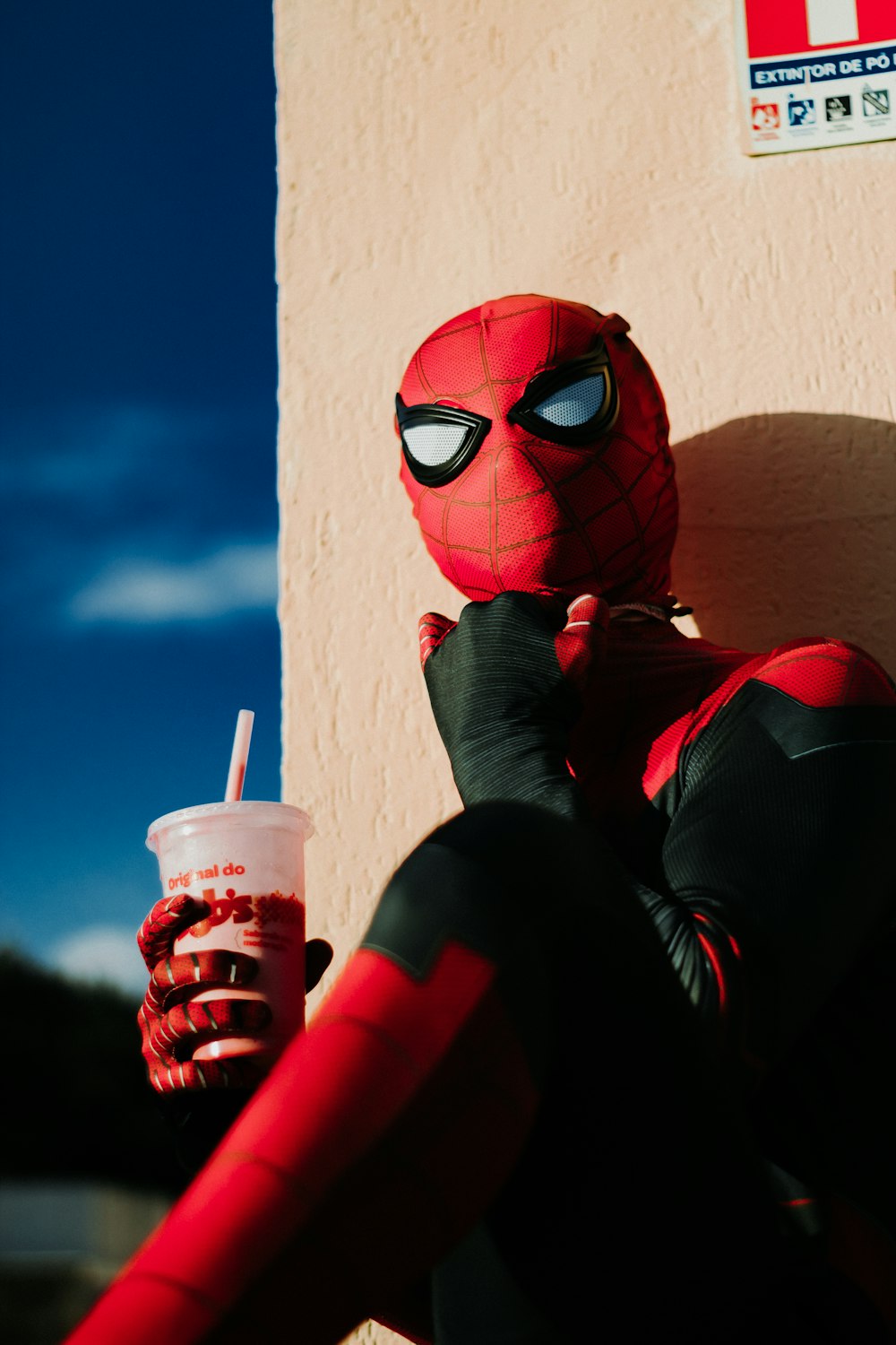 a person in a spiderman costume holding a drink