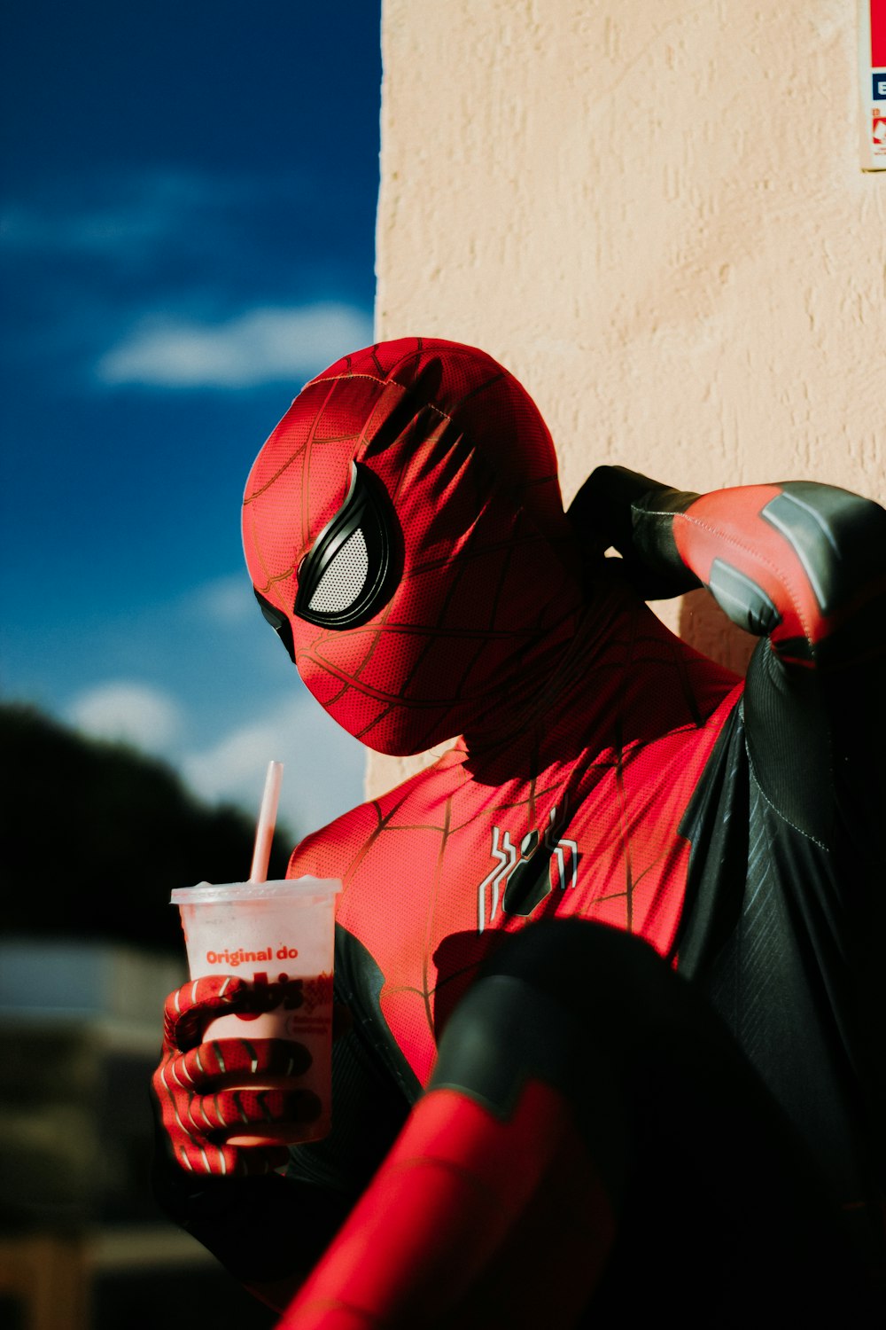 a man in a spiderman costume holding a drink