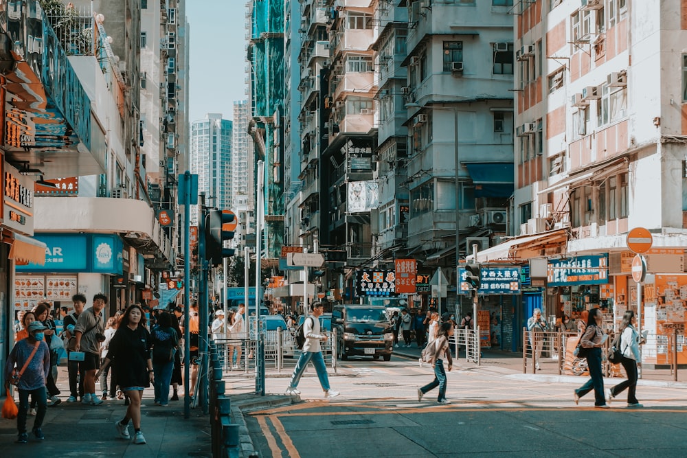 a group of people walking down a street next to tall buildings