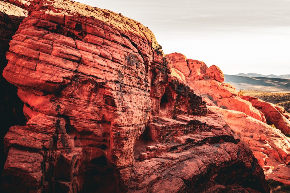 a red rock formation with mountains in the background