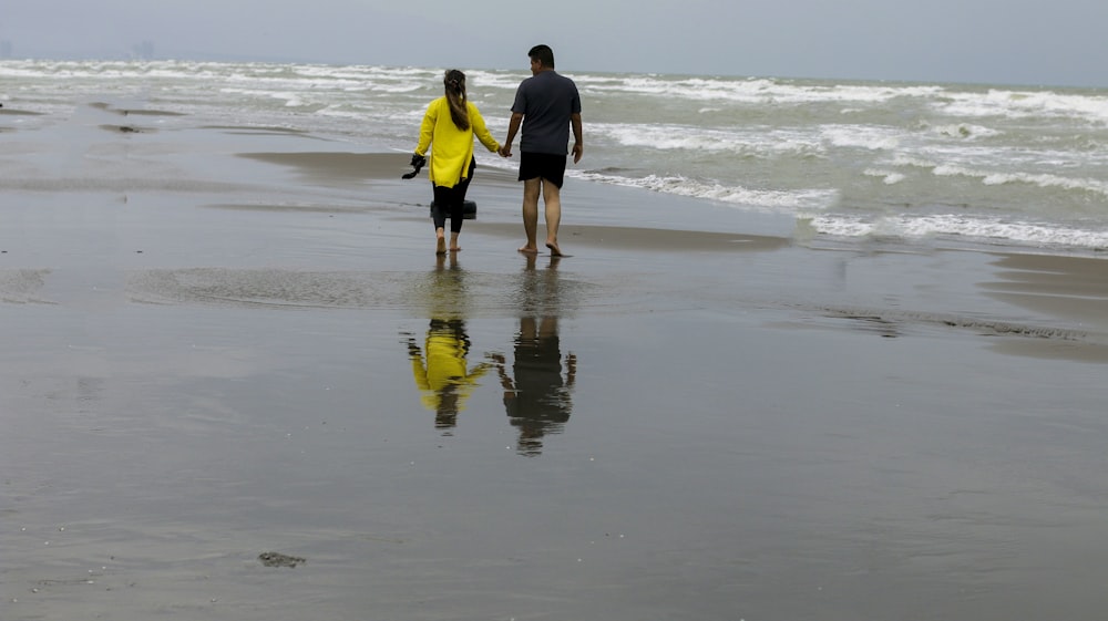 a man and a woman walking on a beach holding hands