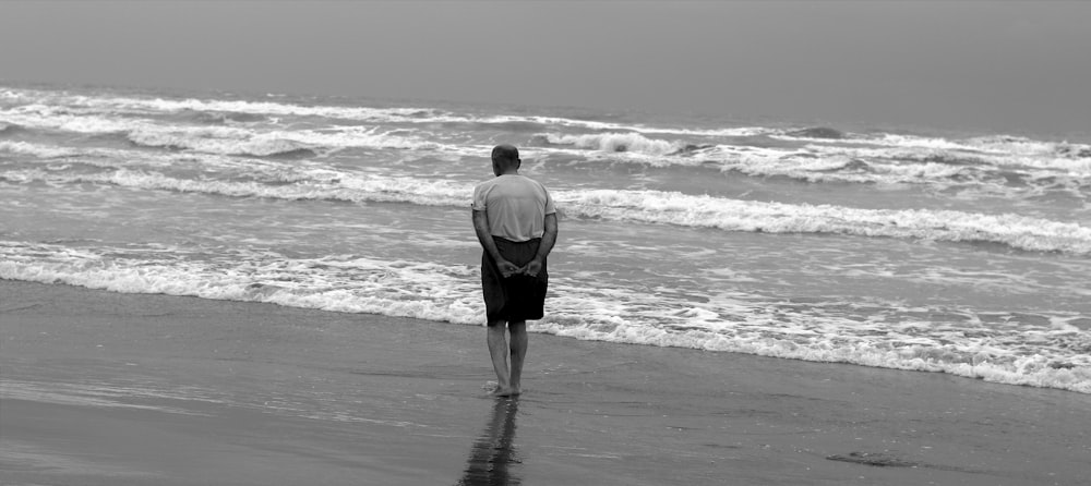 a man standing on top of a beach next to the ocean