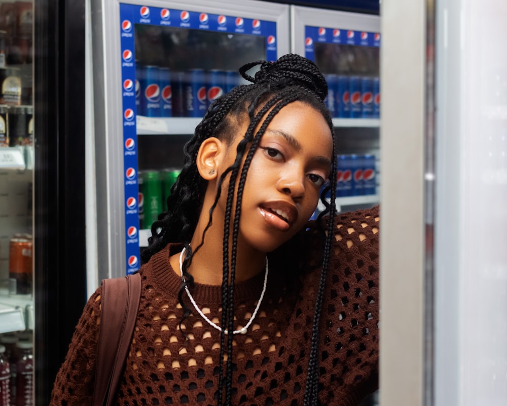 a woman with braids standing in front of a refrigerator