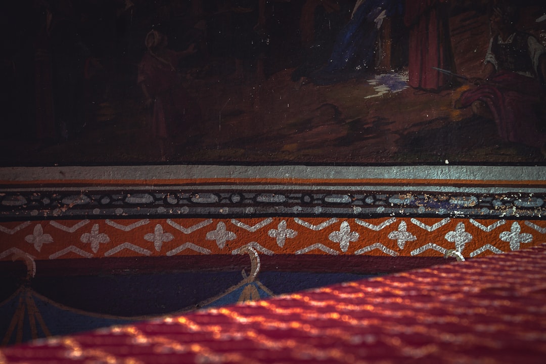 a bed with a red bedspread and a painting on the wall,