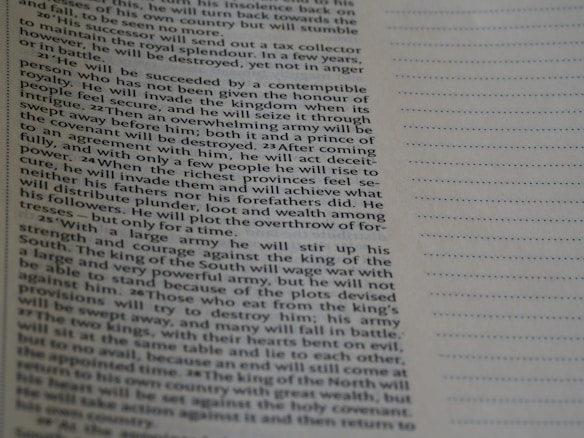 A close-up view of a printed text page with neatly aligned paragraphs on the left and dotted lines on the right side. The text appears to be from a book, possibly religious or historical, given the structured and formal style of writing. The focus is on the text with a shallow depth of field, blurring the lower part of the page.