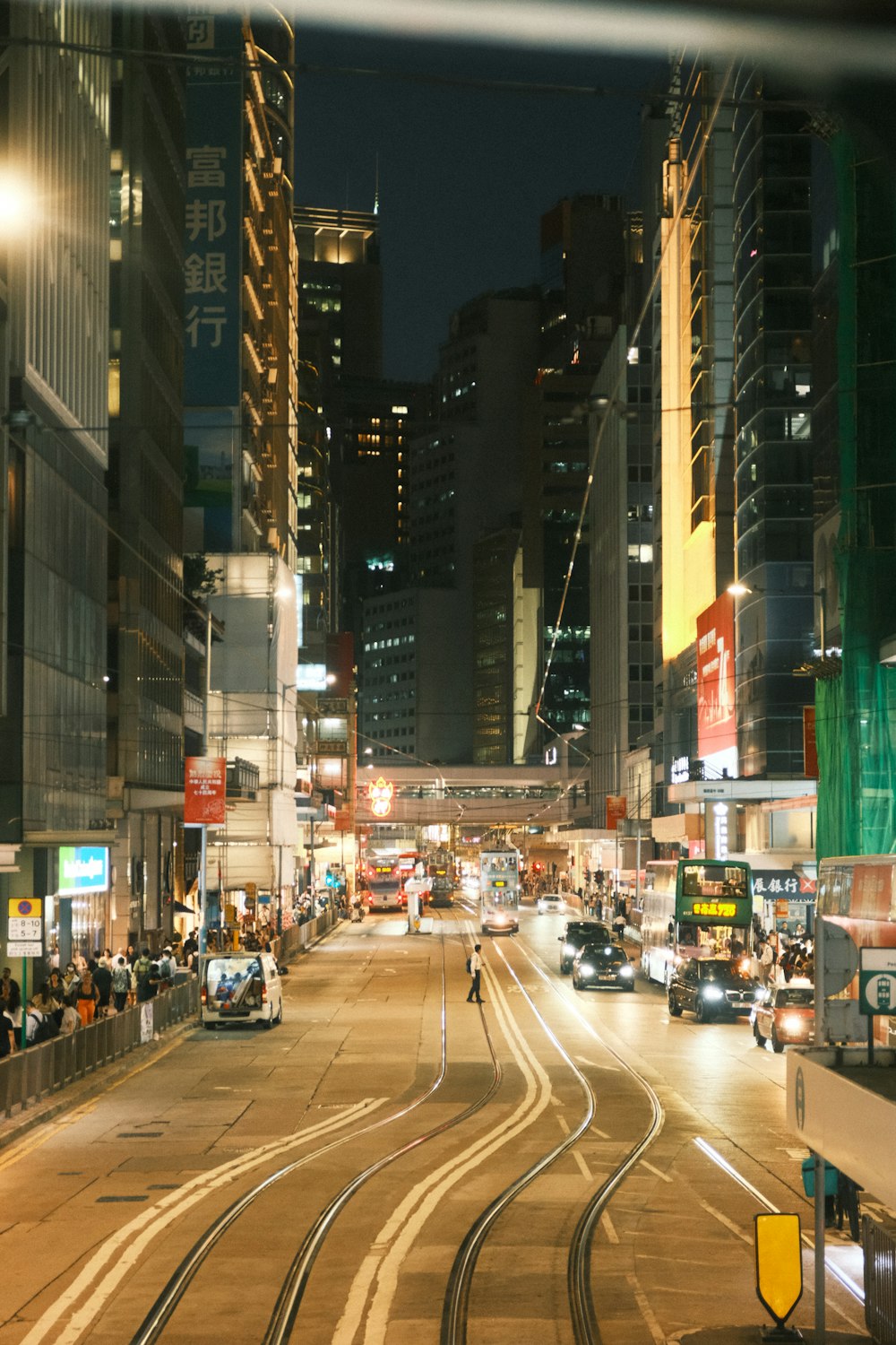 a busy city street at night with a train on the tracks