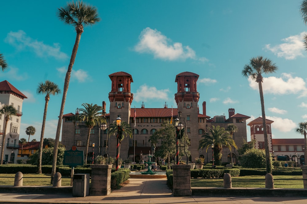 a large building surrounded by palm trees on a sunny day