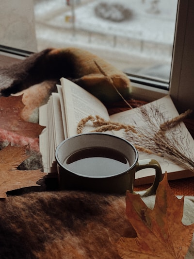 A cozy writing nook with a notebook, pen, and a steaming cup of tea by a window.
