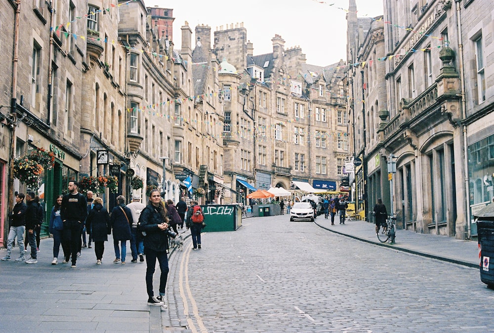 a group of people walking down a street next to tall buildings