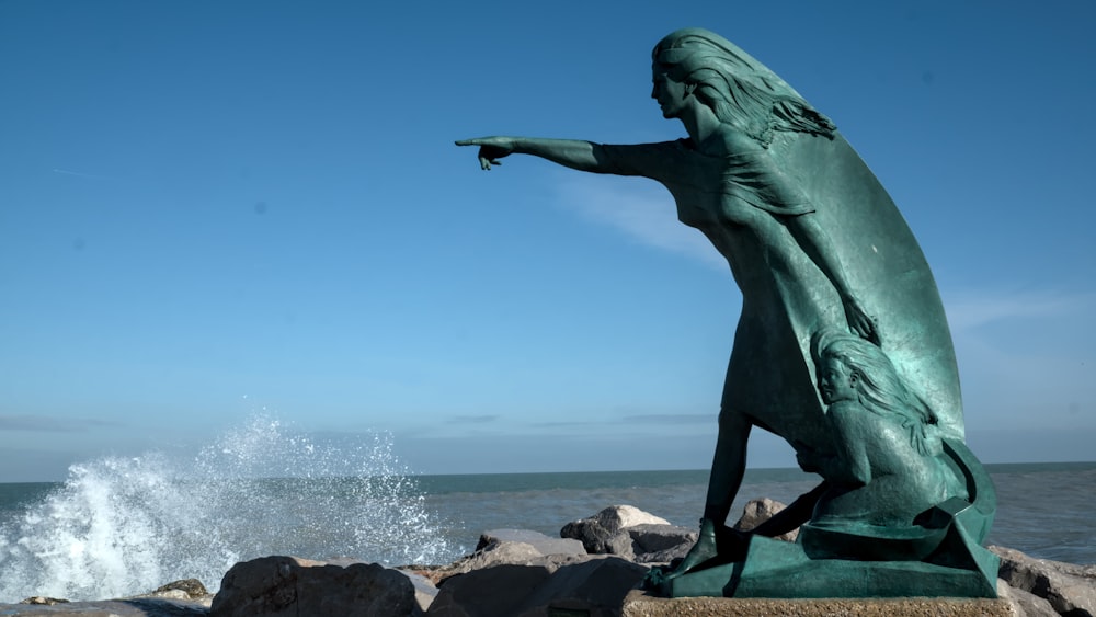a statue of a woman pointing at the ocean