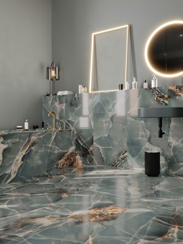 A modern bathroom features luxurious green and white marble surfaces throughout, including the walls, countertop, and floor. There is a rectangular mirror with a soft glow of LED lighting surrounding it and a circular mirror emits a warm ambient light. The gold fixtures, including a faucet, add an elegant touch. Various bottles and toiletries are neatly arranged on the countertop. The overall design is sleek and sophisticated.