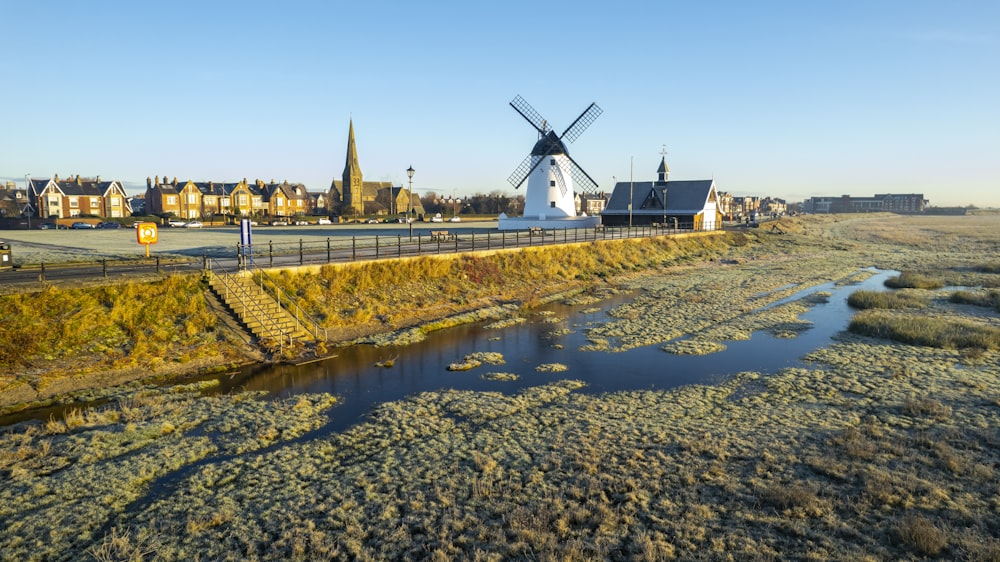 a windmill in a field next to a body of water