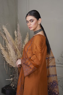 a woman in a brown dress standing next to a plant
