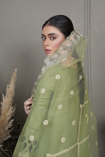 a woman in a green dress with a veil over her head