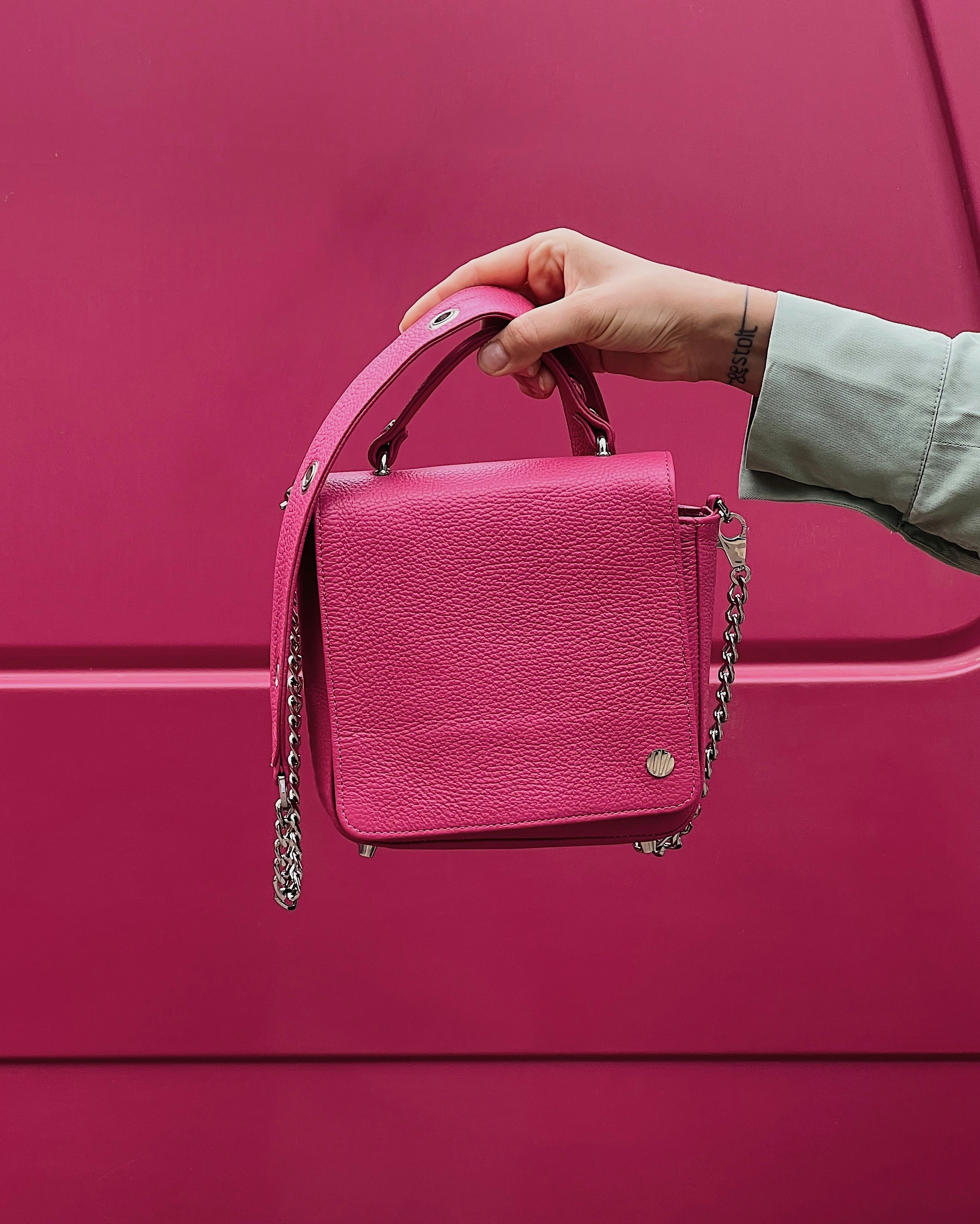 a woman's hand holding a pink purse