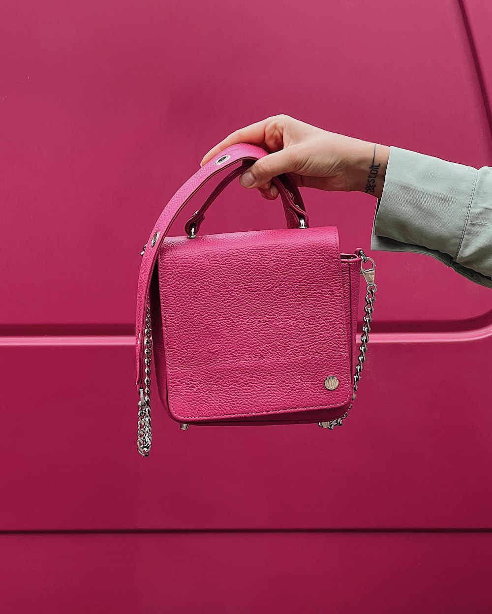 a woman's hand holding a pink purse